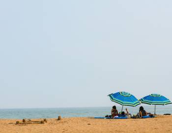family on beach under umbrellas